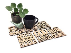 Blank houten onderzetters met uitgesneden teksten.