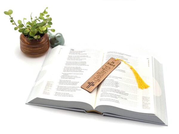 Foto van een boekenlegger in een bijbel met daarop afgebeeld een kruis en de tekst "je bent geliefd".