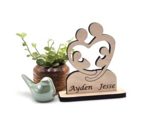 Houten item van twee ouders die twee kinderen omarmend. Het geboorte cadeau is gepersonaliseerd met de namen van de kinderen.