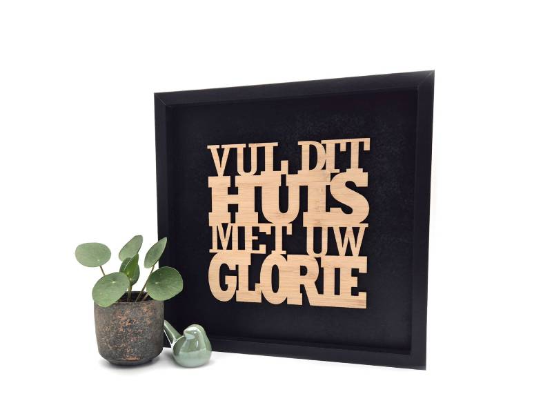 Ingelijste decoratie met de tekst “Vul dit huis met Uw glorie” naast een plant en keramieken vogeltje als christelijke woonaccessoire.