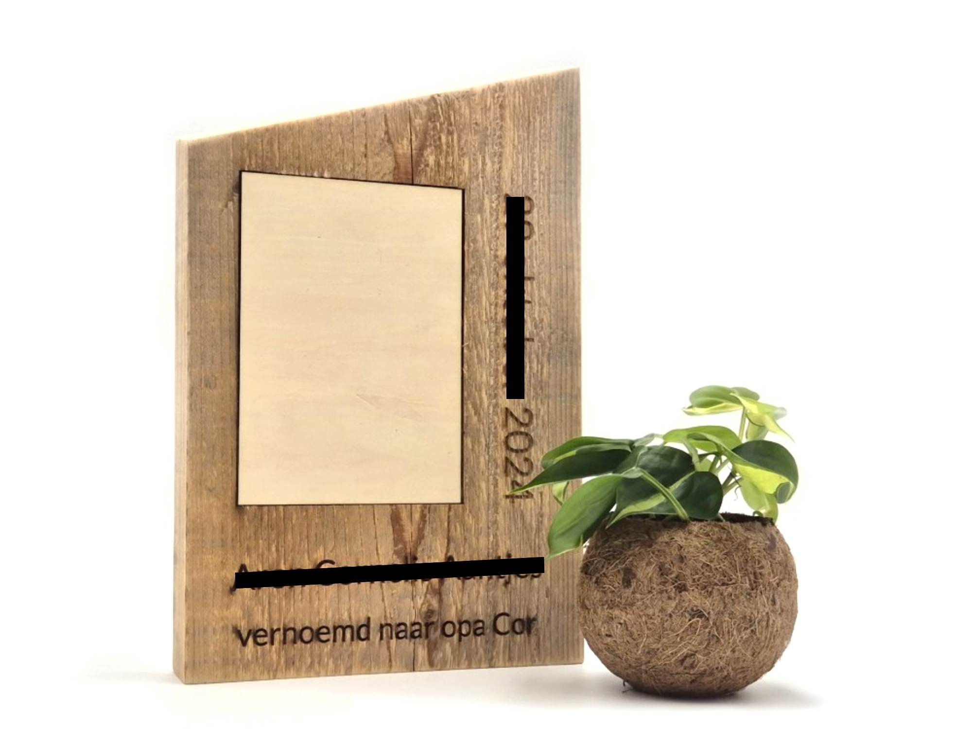 Wat geef je een 88-jarige timmerman als aandenken aan zijn pasgeboren achterkleinkind? Precies! Een fotolijst gemaakt van het robuuste hout waar hij graag mee werkte. Het lichtgekleurde stuk hout kan eruit en op die plek komt een foto van hemzelf met zijn achterkleinkind.  Wegens privacy redenen zijn de naam en geboortedatum van het kind onleesbaar gemaakt.