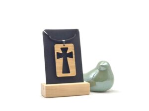 Houten dogtag met uitgesneden kruis aan een zwart leren ketting.