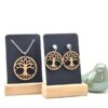 Een set van handgemaakte, houten sieraden met hangers in de vorm van een levensboom. De ketting en de oorprikkers zijn van roestvrijstaal.