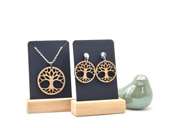 Een set van handgemaakte, houten sieraden met hangers in de vorm van een levensboom. De ketting en de oorprikkers zijn van roestvrijstaal.